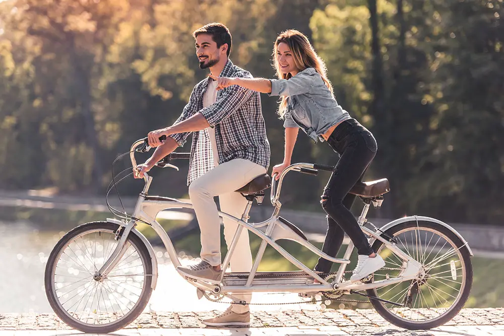 A young couple enjoying a tandem bike ride along Miami South Beach.